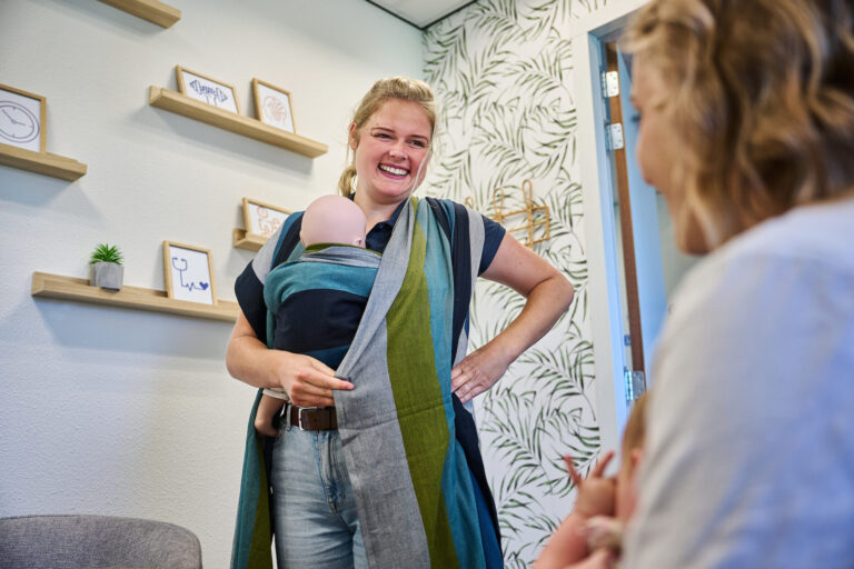 Goed voorbereid op pad: Waarom een draagconsult al tijdens je zwangerschap begint De komst van een kleintje verandert alles. Je wilt je baby straks het liefst de hele dag dicht bij je houden, maar je wilt ook je handen vrij hebben voor een kop thee of een korte wandeling. De oplossing? Je kindje dragen in een doek of ergonomische zak. Bij onze kinderfysiotherapiepraktijk merken we dat de meeste ouders pas aan dragen denken áls de baby er eenmaal is. Maar wist je dat het ook heel rustig en fijn kan zijn om dit al vóór de geboorte te leren? Waarom een consult tijdens je zwangerschap? De kraamtijd is een prachtige, maar ook intensieve periode. Je bent aan het herstellen, je baby moet wennen aan de wereld en je ritme ligt volledig overhoop. Dat is vaak niet het ideale moment om met een lange lap stof en een instructievideo te gaan stoeien. De voordelen van voorbereiden in de zwangerschap: Oefenen in alle rust: Je leert de knooptechnieken of het afstellen van een drager zonder dat je baby onrustig wordt of begint te huilen. Spiergeheugen opbouwen: Door tijdens je zwangerschap al een paar keer te oefenen met onze speciale verzwaarde oefenpop, zit de handeling in je systeem. Direct vanaf dag één: Zodra je baby geboren is, kun je hem of haar direct veilig en verantwoord bij je dragen. Geen onzekerheid, maar direct genieten van dat intieme contact. Het juiste advies: Er is enorm veel keuze. Wij helpen je tijdens je zwangerschap alvast te ontdekken welk systeem (doek of zak) echt bij jouw lichaam en wensen past. De blik van de kinderfysiotherapeut Omdat wij naar het hele plaatje kijken, adviseren we niet alleen over de doek zelf. We kijken naar de ergonomie voor zowel jou als je baby. Voor je baby: We leren je hoe je je pasgeboren kindje in de gezonde 'M-houding' (kikkerhouding) plaatst. Dit is essentieel voor een goede heupontwikkeling en ondersteunt de natuurlijke bolling van de rug. Voor jou: Na de bevalling moet je lichaam herstellen. Wij leren je hoe je het gewicht van je baby optimaal verdeelt, zodat je je bekken en rug ontlast in plaats van verkeerd belast. Vorm Hoe ziet een pre-nataal draagconsult eruit? In een ontspannen sessie bij ons in de praktijk nemen we de verschillende opties door. We hebben diverse ergonomische dragers en doeken klaarliggen. Je oefent met onze draagpop, die het gewicht en de beweeglijkheid van een echte baby simuleert. Zo voel je precies wat een bepaalde knoop of drager met je eigen houding doet. Na de geboorte kun je (indien gewenst) nog een korte check-up inplannen om samen met je baby de puntjes op de i te zetten, maar de basis heb je dan allang in de vingers! Vorm Wil jij ook een vliegende start maken en je baby direct na de geboorte zelfverzekerd kunnen dragen? Plan dan nu een draagconsult in tijdens je zwangerschap. Zo ben je helemaal klaar voor die eerste bijzondere momenten samen.